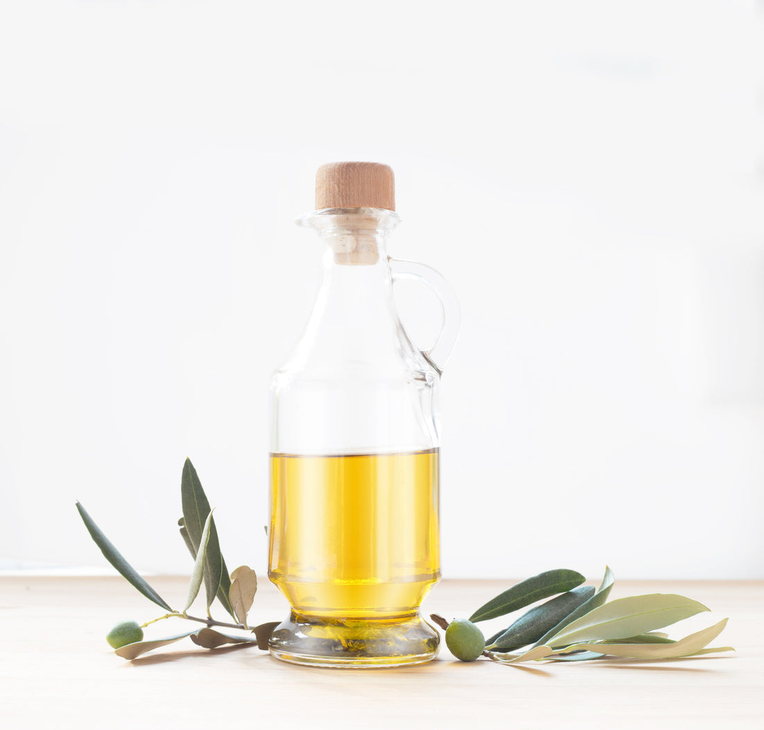 Glasflasche mit Olivenöl und einem Olivenzweig
